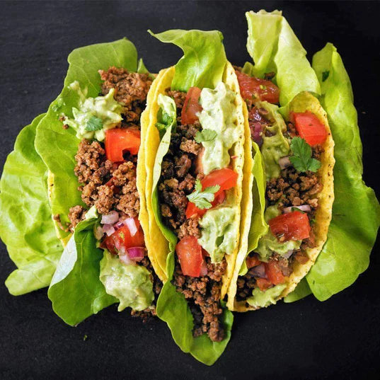vegetarian taco meat substitute featured in lettuce wrap tacos with tomato guacamole and onion inside
