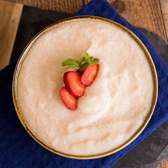 strawberry flavored cream of wheat with strawberry slices on top in bowl on blue towel