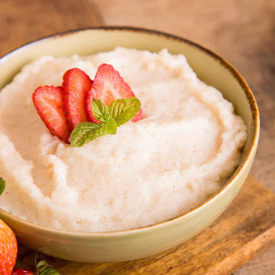 strawberry flavored cream of wheat in tan bowl with strawberry slices on top and green garnish