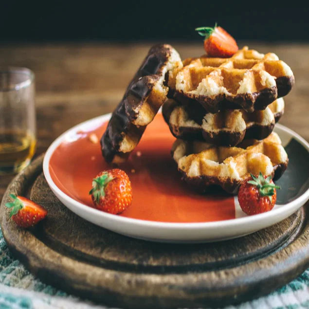 chocolate dipped waffles with strawberries on top on multicolored plate