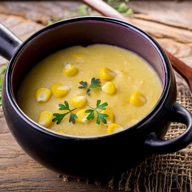 corn chowder in purple dish with green garnish on top