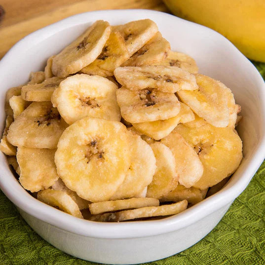 banana chips in white bowl on green cloth