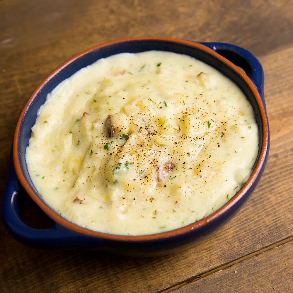 homestyle potato soup in blue and orange dish on wooden surface