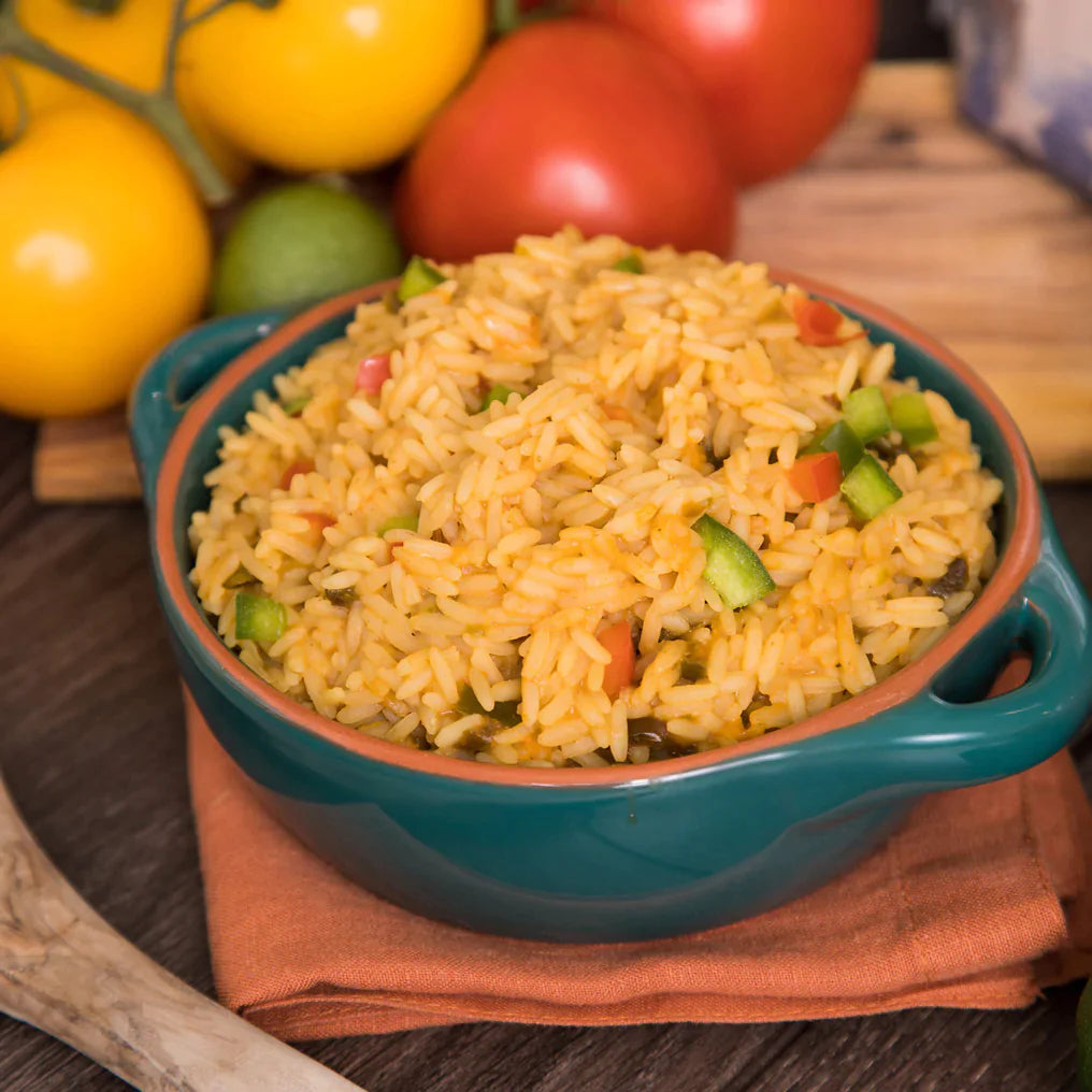 southwest rice in blue and orange bowl on orange clothe with various vegetables in background