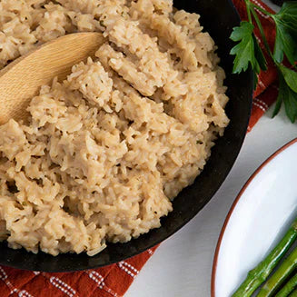 up close mushroom rice pilaf in black bowl with wooden spatula sticking out