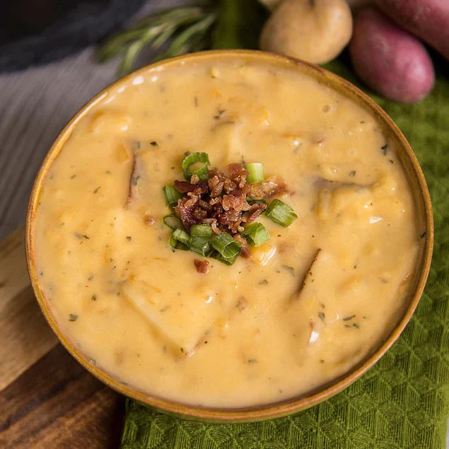 potato cheddar soup in yellow bowl with bacon and chives on top