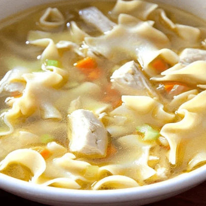 chicken flavored noodle soup up close image featuring chicken noodles carrots and celery in broth